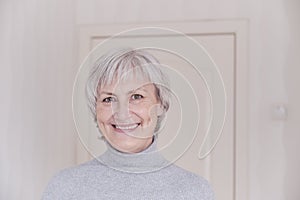 A close-up portrait of a smiling elderly Caucasian woman with short gray hair