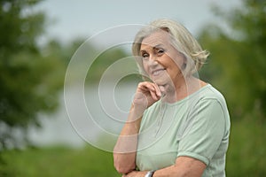 Close-up portrait of smiling elderly woman posing in summer park