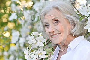 Close-up portrait of smiling elderly woman posing in summer park