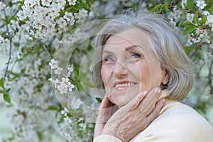 Close-up portrait of smiling elderly woman posing in summer park