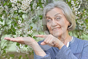 Close-up portrait of smiling elderly woman posing in summer park