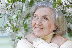 Close-up portrait of smiling elderly woman posing in summer park