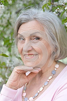 Close-up portrait of smiling elderly woman posing in summer park