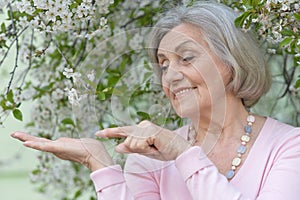 Close-up portrait of smiling elderly woman posing in summer park