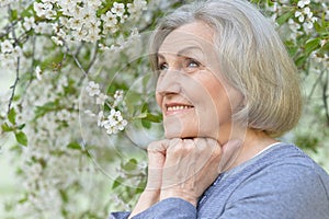 Close-up portrait of smiling elderly woman posing in summer park