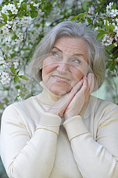 Close-up portrait of smiling elderly woman posing in summer park