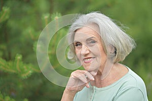 Close-up portrait of smiling elderly woman posing in summer park