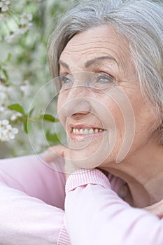 Close-up portrait of smiling elderly woman posing in summer park