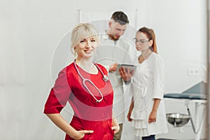 Close-up portrait of a smiling female doctor in a red uniform with a stethoscope.