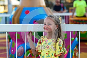 Close-up portrait of smiling girl near the carousel at the fair. Portrait of a cute girl on the background of an amusement park