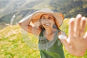 Close up portrait of a smiling happy elderly traveling woman tourist posing against the backdrop of mountains. Old