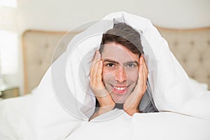 Close up portrait of a smiling man resting in bed