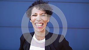 Close up portrait of smiling mature businesswoman in suit standing against blue wall