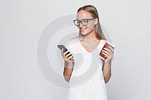 Close up portrait of a smiling pretty woman in hat holding mobile phone  over gray background