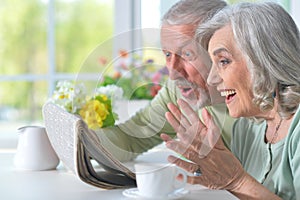 Close-up portrait of a smiling senior couple with newspaper