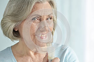 Close-up portrait of smiling senior woman with inhaler