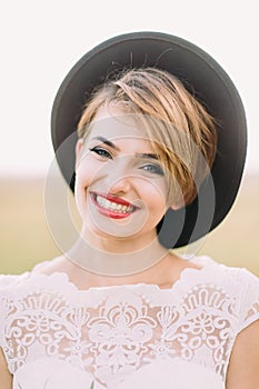 The close-up portrait of the smiling woman with the natural make-up, red lipstick and cat eyes looking at the camera.