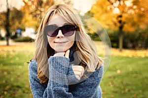 Close-up portrait of smiling woman relaxing in the park and enjoying fall weather