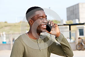 Close up of smiling young black man talking on cellphone outdoors