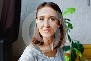 Close-up portrait of a smiling young brunette Caucasian woman looking at the camera, feeling excited and optimistic