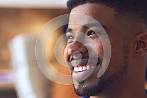 Close Up Portrait Of Smiling Young Businessman At Desk In Modern Office