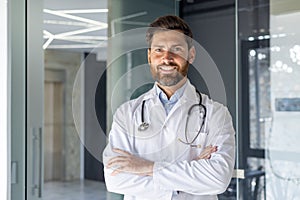 Close-up portrait of a smiling young male doctor, assistant, student standing in the hospital office and confidently