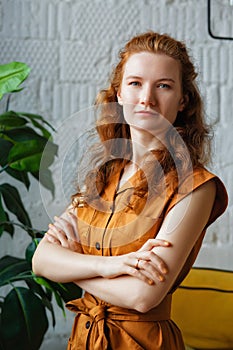 Close-up portrait of a smiling young red-haired Caucasian woman looking at the camera, feeling excited and optimistic