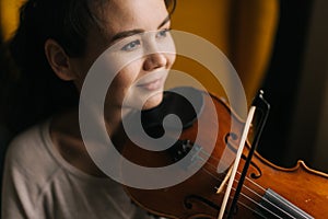 Close-up portrait of smiling young woman musician playing the violin