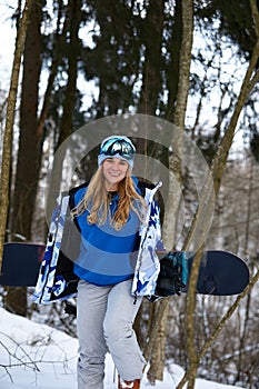 Close up portrait of snowboarder woman at ski resort wearing helmet and goggles with reflection of forest in mountains