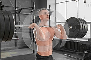 Close up portrait of a sporty man with barbell in gym.