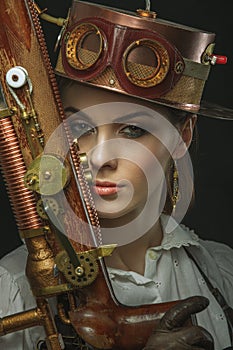 Close-up portrait of steampunk girl with a gun in his hand.