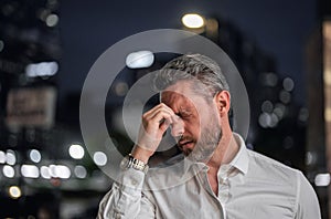 Close up portrait of stressed business man on night city background. Stressed ceo manager have stress and headache