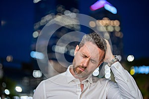 Close up portrait of stressed business man on night city background. Stressed ceo manager have stress and headache