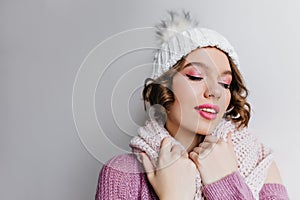 Close-up portrait of stunning girl with bright pink makeup. Indoor photo of refined young woman in cute white hat and