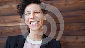 Close up portrait of successful mature businesswoman laughing against wooden wall