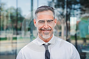 Close up portrait of successful mature caucasian business man smiling looking at camera standing outdoors at workplace