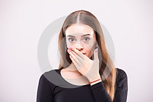 Close-up portrait of surprised attractive woman covering her mouth by the hands, over white background