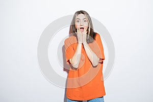Close-up portrait of surprised beautiful girl holding her head in amazement and open-mouthed over white background