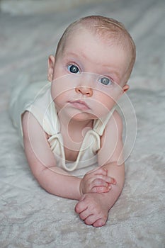 Close-up portrait of surprised cute baby lying on the bed.