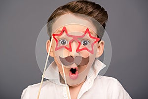 Close up portrait of surprised funny schoolboy holding props