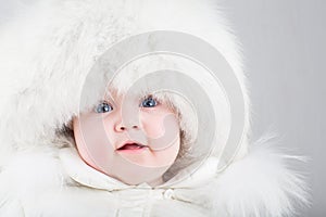 Close up portrait of a sweet baby in a white fur hat