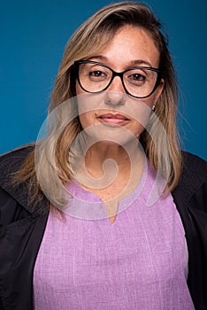 Close-up portrait of sweet confident female doctor dressed in black coat and lilac uniform, wearing eyeglasses, looking at camera