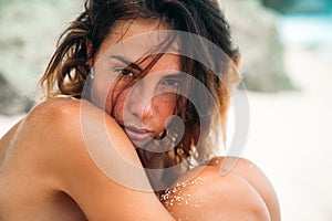 Close-up portrait of a tanned girl on the beach. A gorgeous model with a tight-fitting sports figure in a red