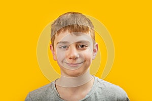 Close up portrait of teenage boy with brown hair and brown eyes smiling and looking into the camera on yellow background