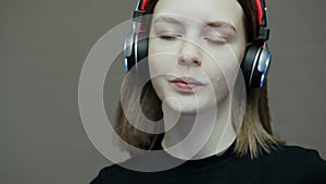 Close-up portrait of teenage girl puts on wireless headphones and enjoying music, dancing