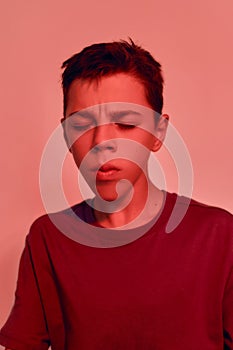 Close up portrait of teenaged disabled boy with cerebral palsy keeping his eyes closed, suffering from pain, posing