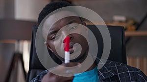 Close-up portrait of thoughtful serious young man looking at pen thinking. Intelligent concentrated African American