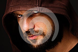 Close-up portrait of threatening man with beard wearing a hood