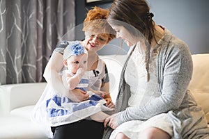 Close up portrait of three generations of women being close, grandmother, mother and baby daughter at home