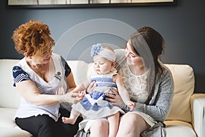 Close up portrait of three generations of women being close, grandmother, mother and baby daughter at home